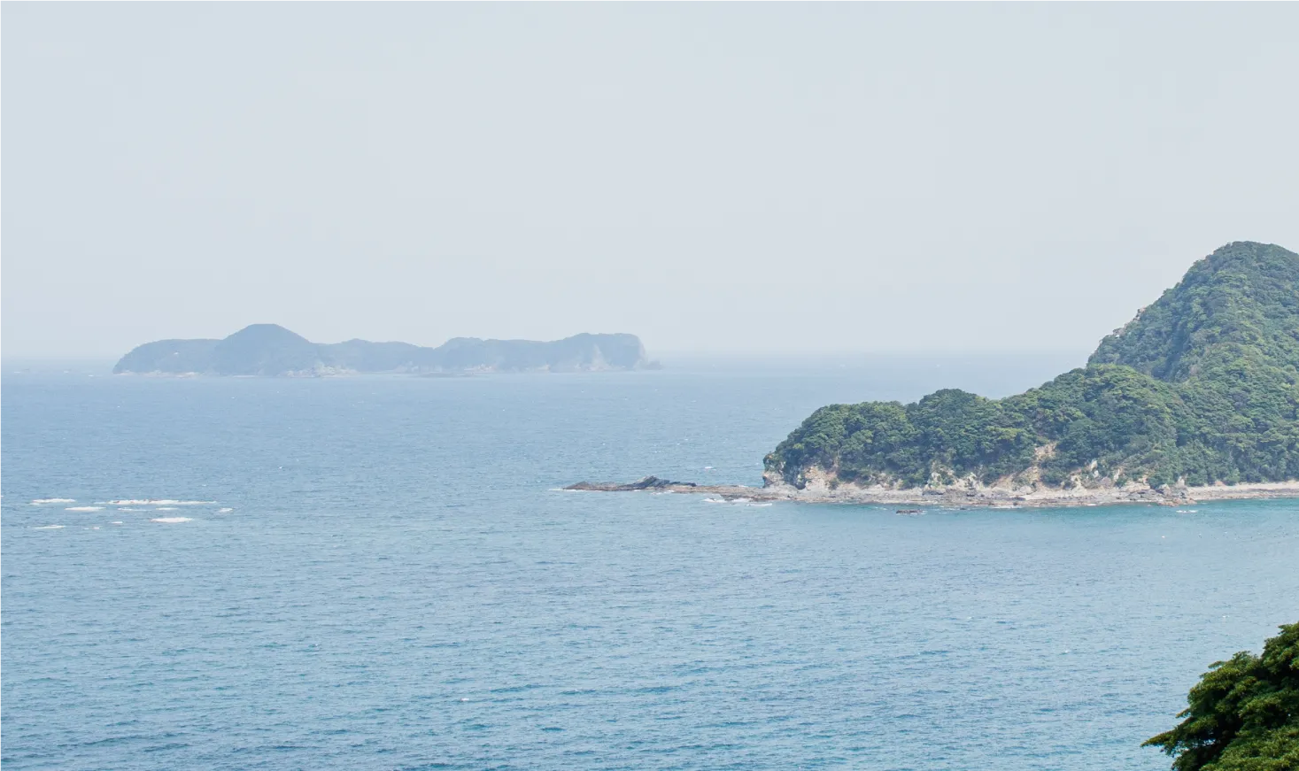 穏やかな海の向こうに浮かぶ島々と緑の海岸